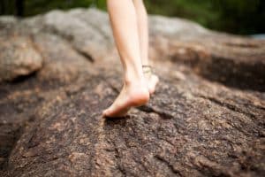 behind young person walking on rock barefoot