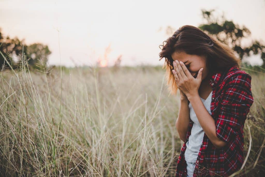 Close up of sad young woman in a field.