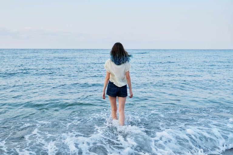 Happy beautiful teenager girl enjoying sea water, sea evening nature, back view